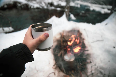 person holding white ceramic mug with fire