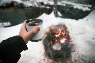 person holding white ceramic mug with fire