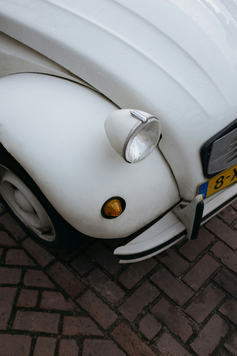 Volkswagen Beetle blanco sobre piso de ladrillo gris