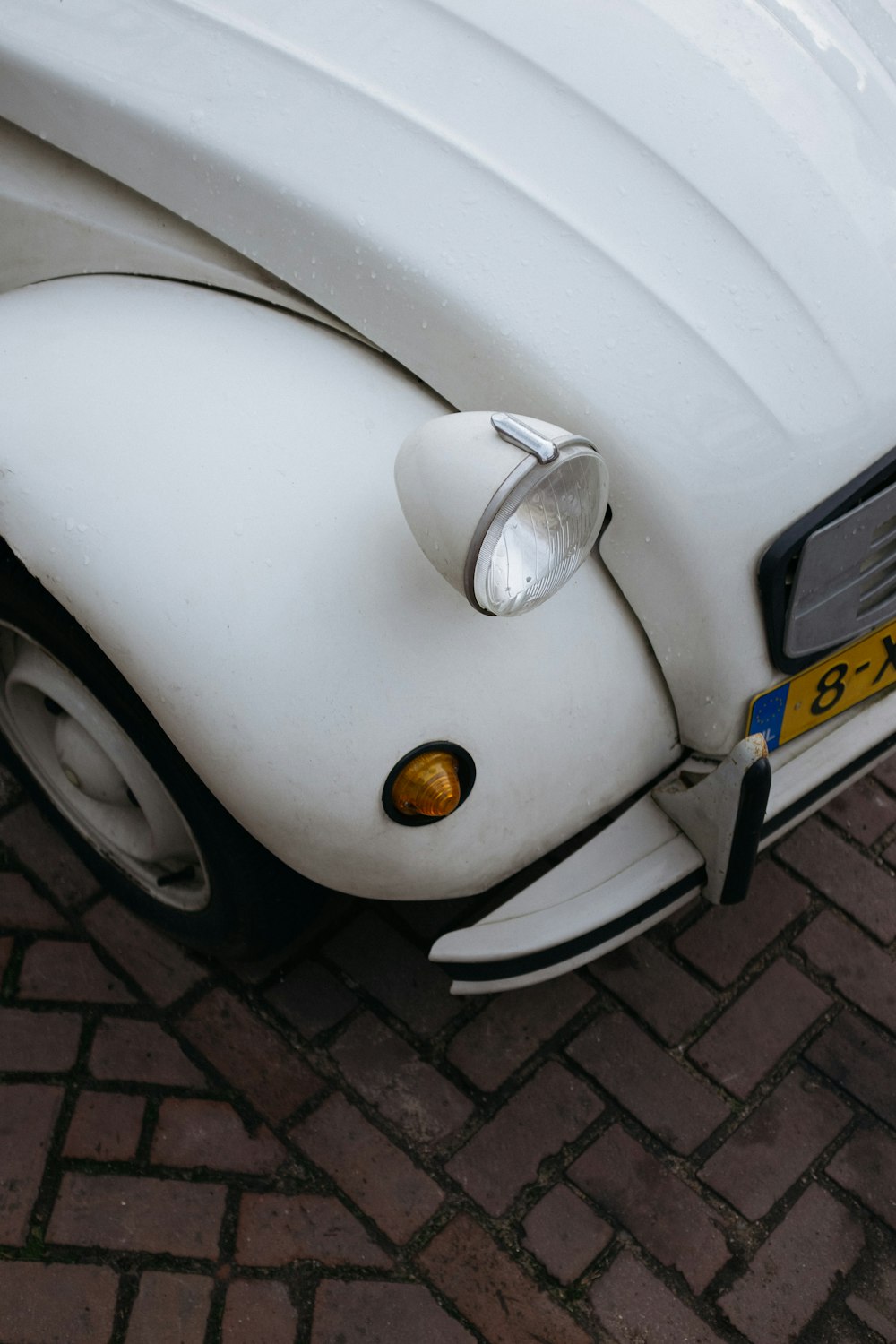 Maggiolino Volkswagen bianco su pavimento in mattoni grigi