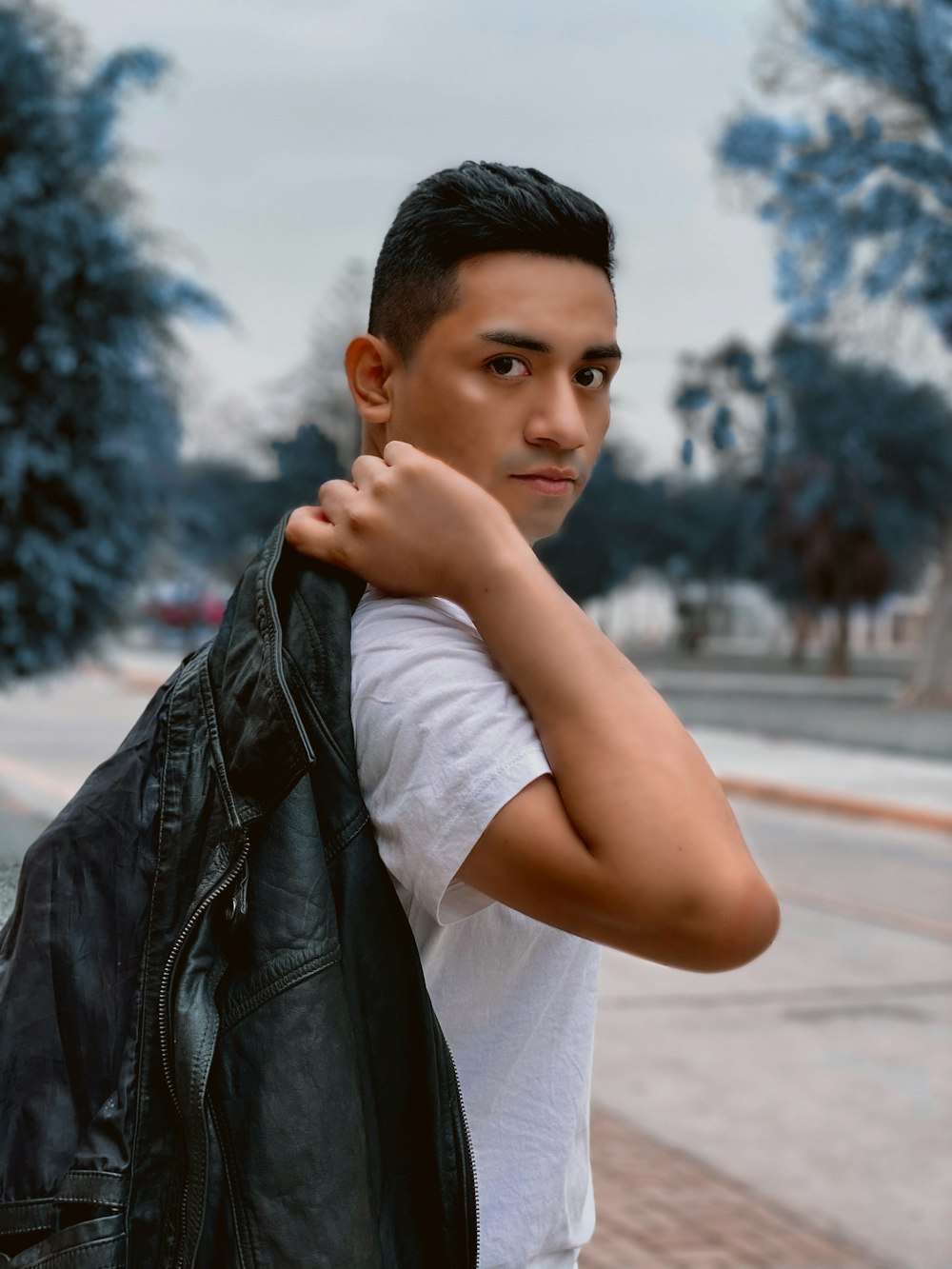 man in white t-shirt holding black leather jacket