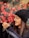 woman in black knit cap and black framed eyeglasses holding red flowers