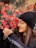 woman in black knit cap and black framed eyeglasses holding red flowers