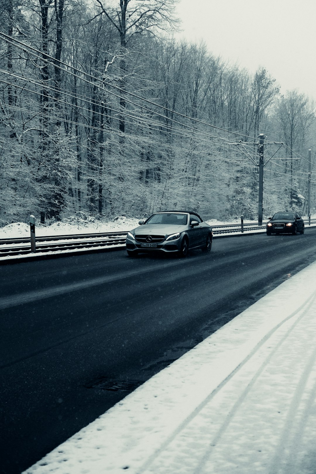 black car on road covered with snow during daytime