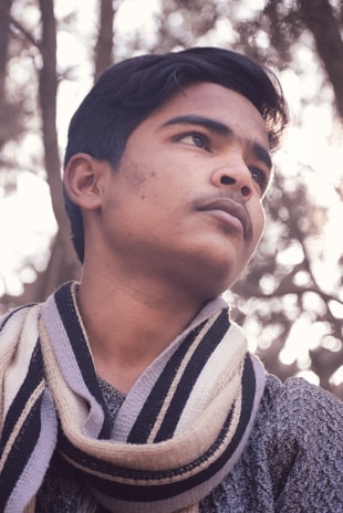 A close-up of a thoughtful pre-teen girl with a gentle smile, wearing a bright scarf.