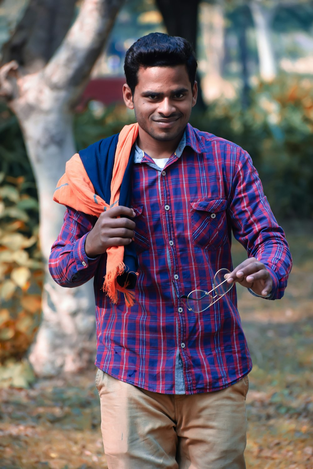 Foto Hombre de camisa de manga larga con botones a cuadros azules y rojos sosteniendo un palo marrón y azul – Imagen India gratis en