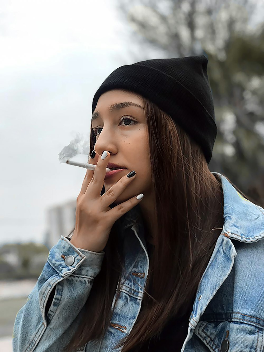 femme en veste en jean bleue fumant une cigarette