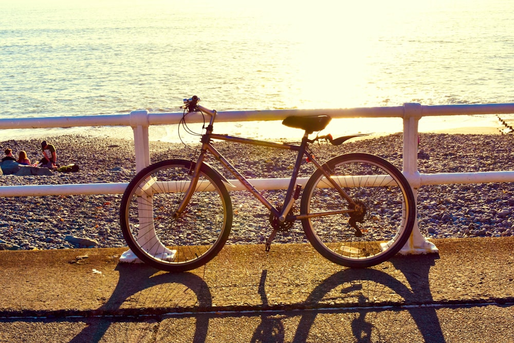 black and white road bike on black metal fence near sea during daytime