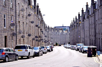 cars parked on side of road near high rise buildings during daytime
