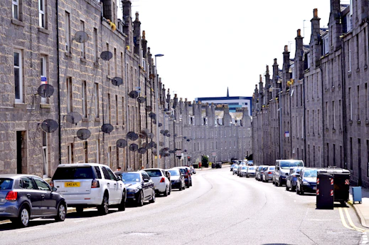 cars parked on side of road near high rise buildings during daytime