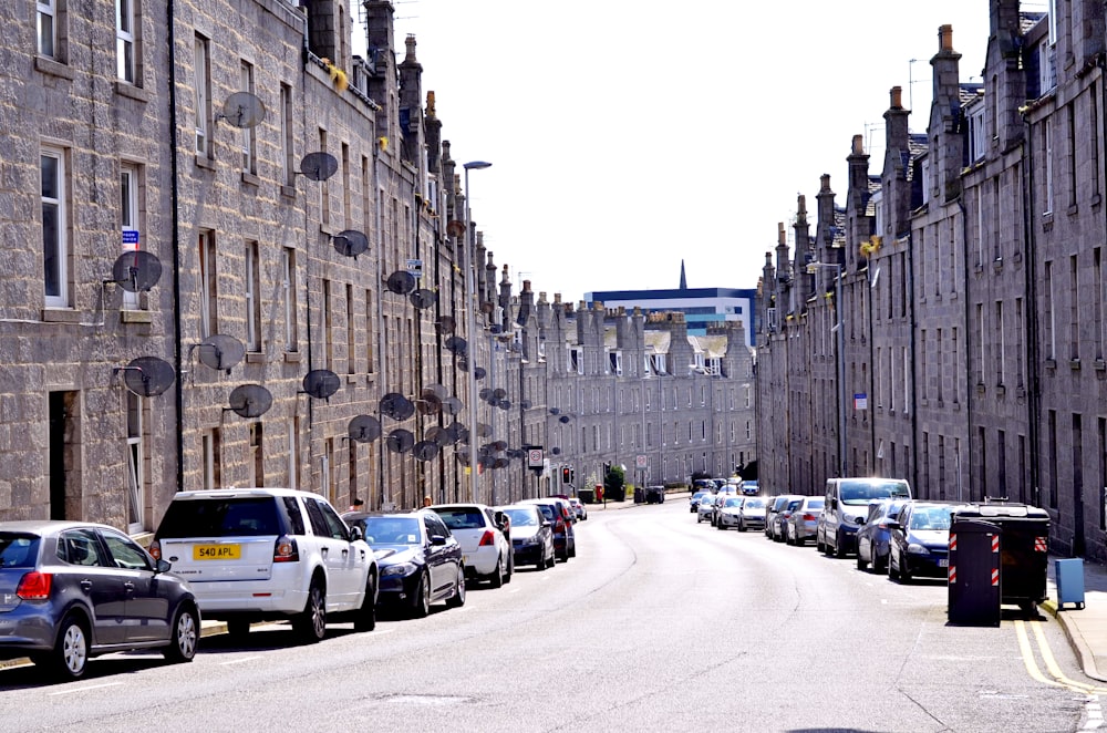 cars parked on side of road near high rise buildings during daytime