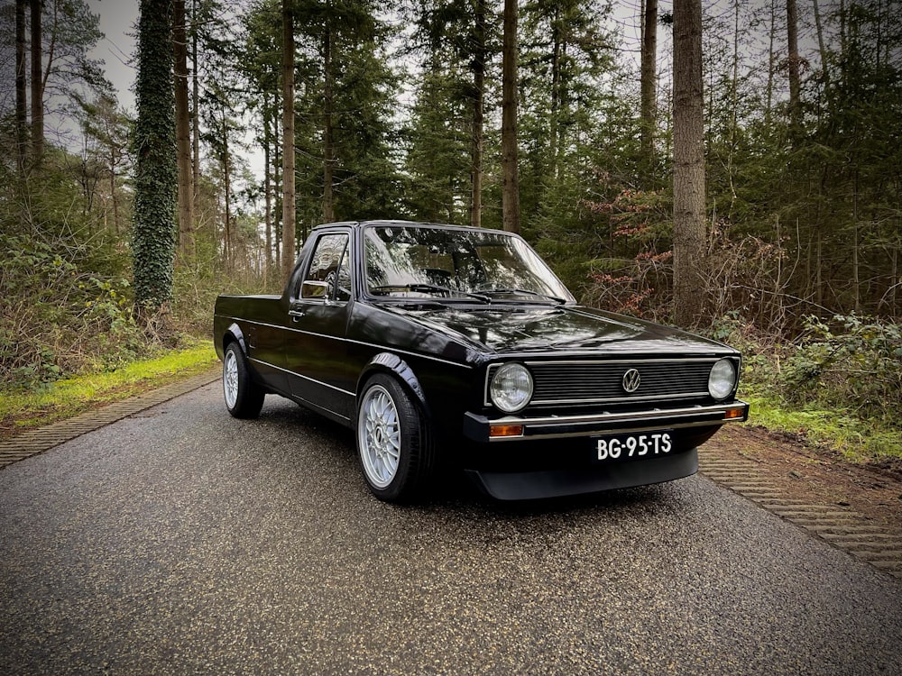 black mercedes benz coupe parked on road near trees during daytime