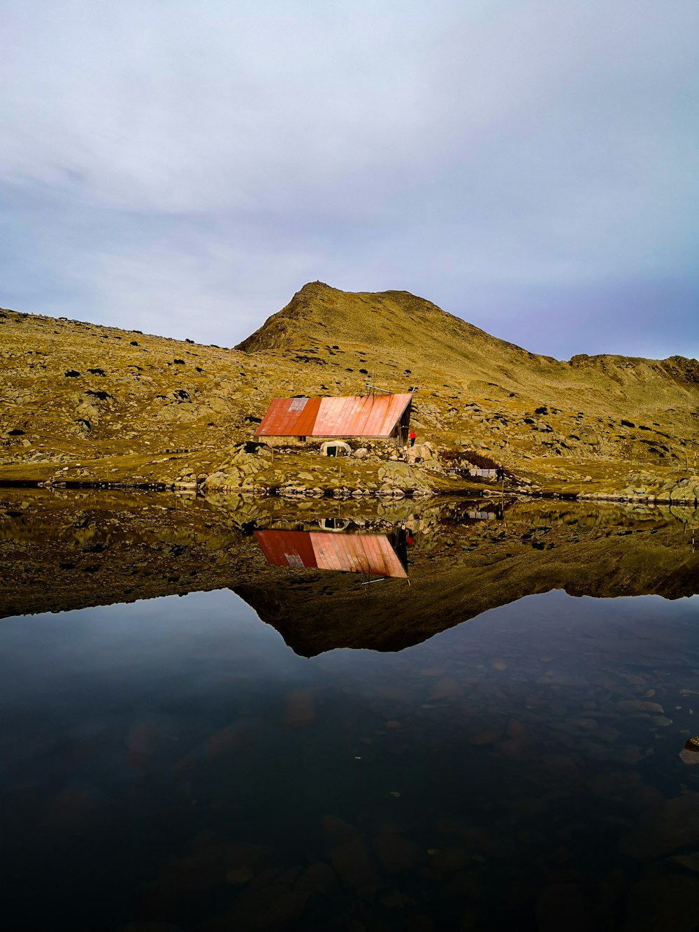 Casa de madera marrón en un campo de hierba verde junto al cuerpo de agua durante el día