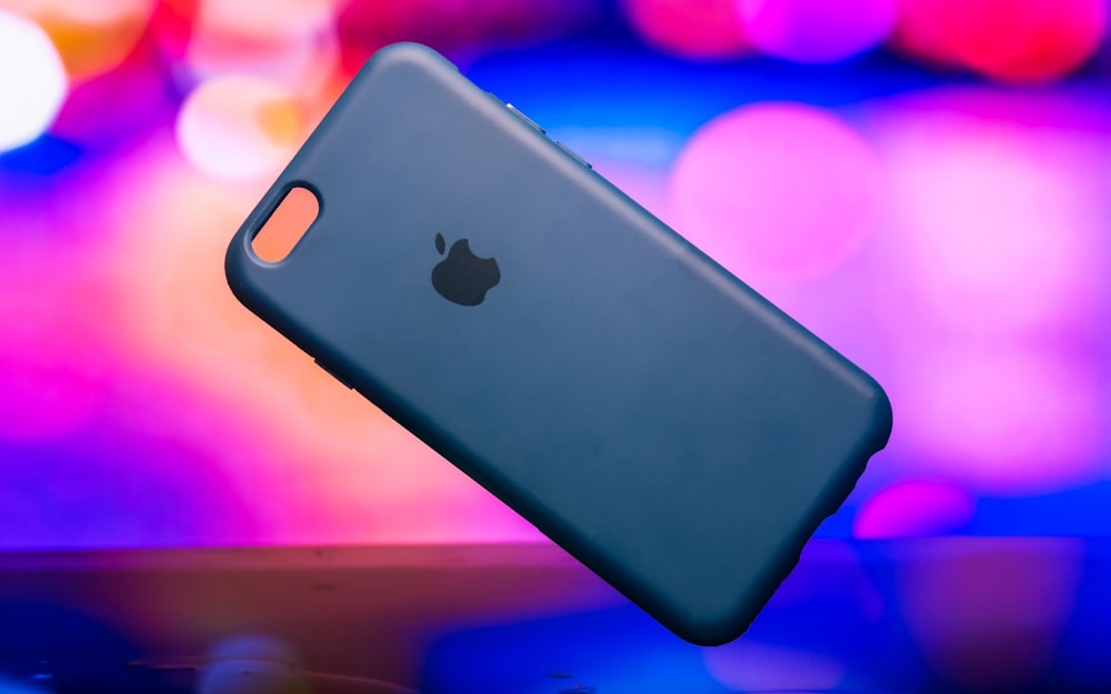 Funda azul para iPhone sobre superficie rosa y verde