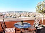 Sunlit terrace with small table and chairs overlooking the city.