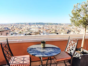 Sunlit terrace with small table and chairs overlooking the city.