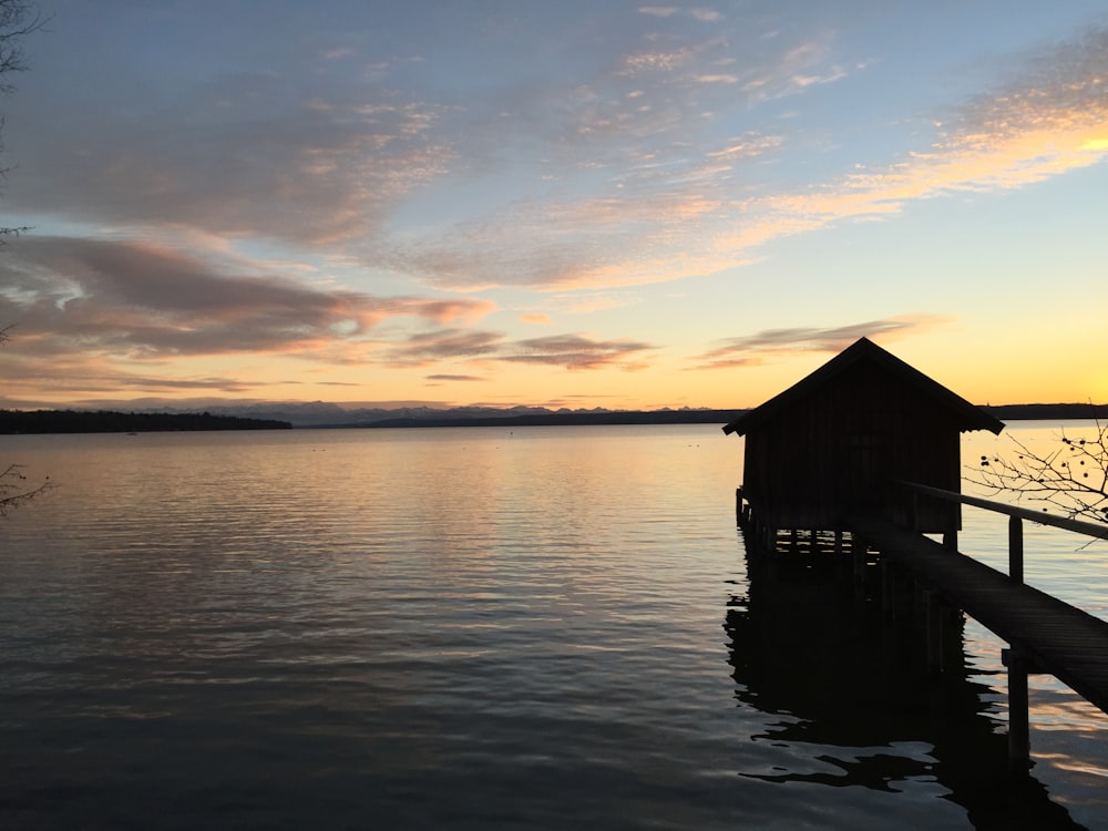 silhouette of house on water during sunset