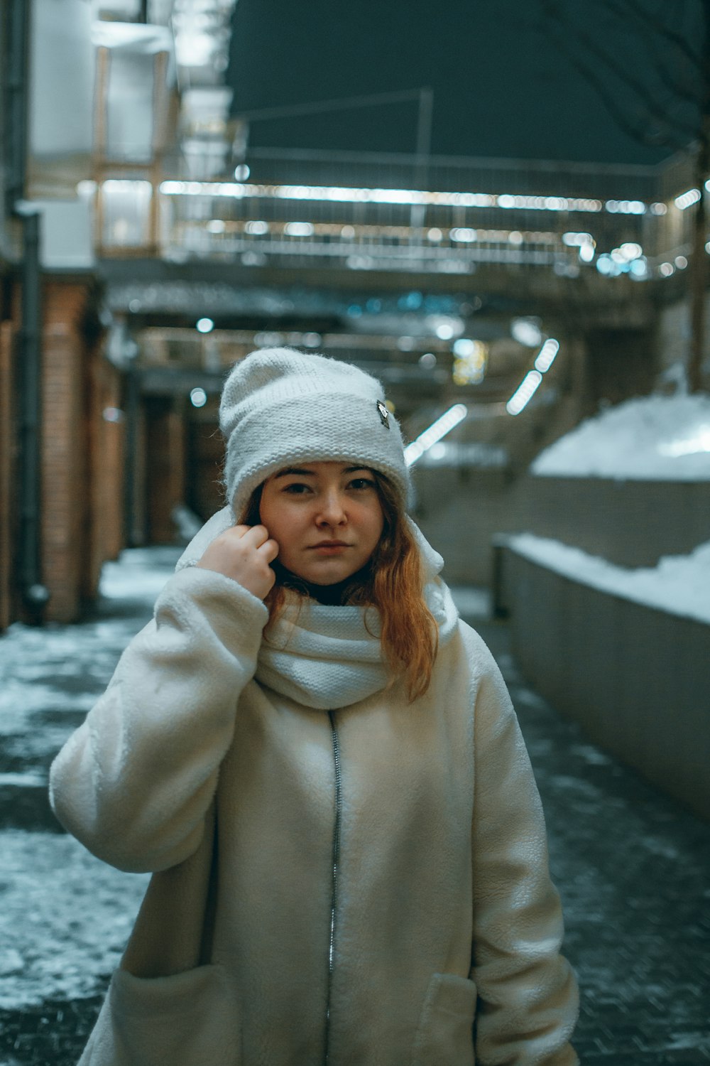 woman in white coat and knit cap standing on snow covered ground during daytime