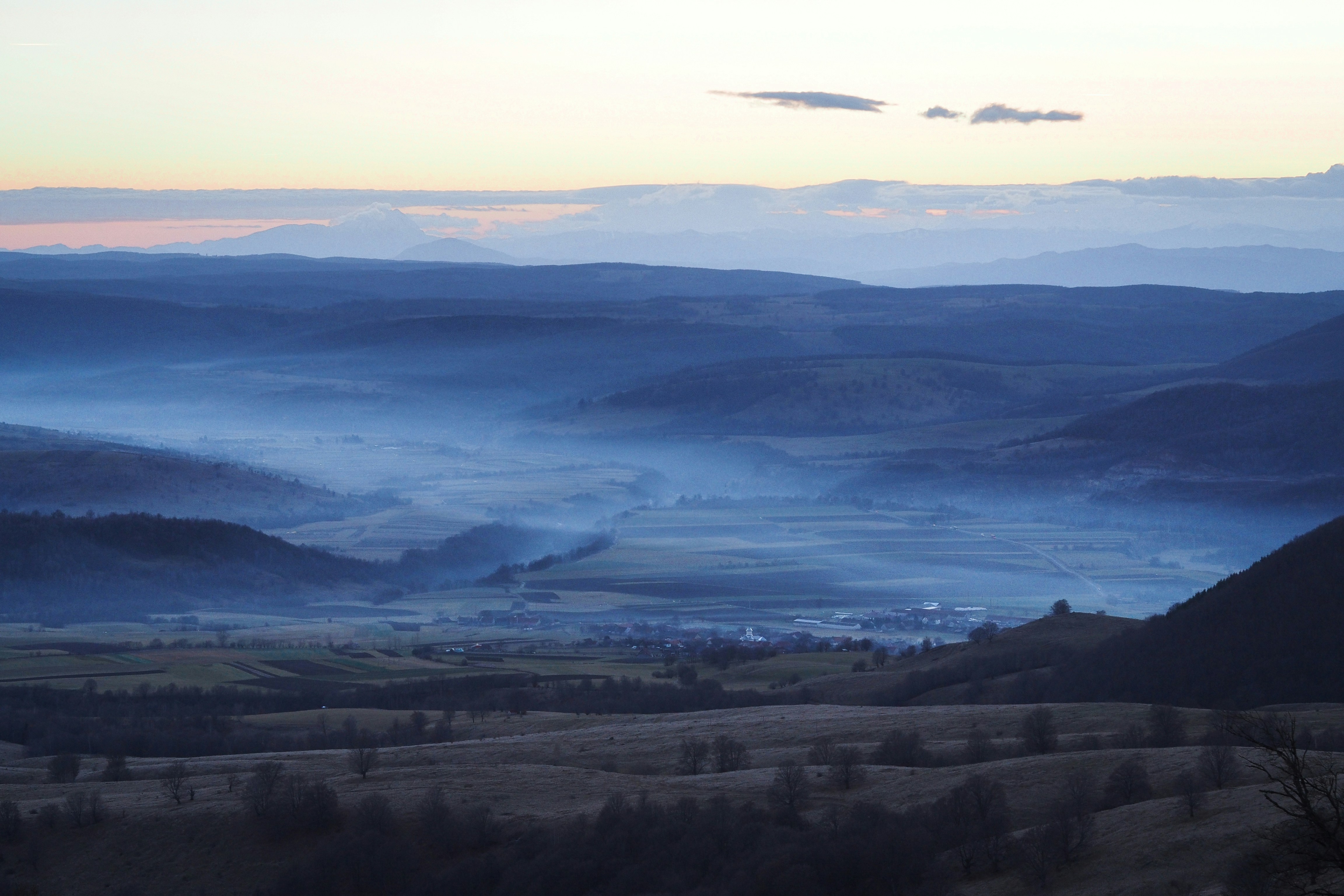 Misty mountain valley at dawn with layers of blue fog, deeply peaceful and expansive, breath and space