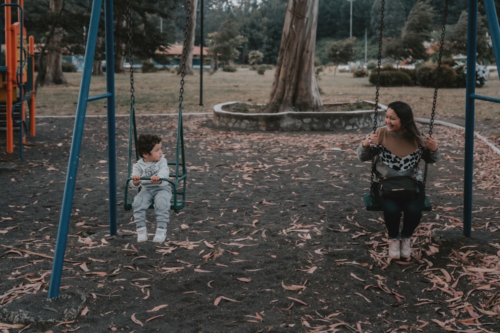 2 children sitting on swing during daytime