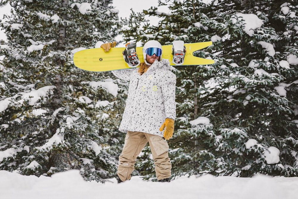 man in white and red floral dress shirt and brown pants holding yellow surfboard