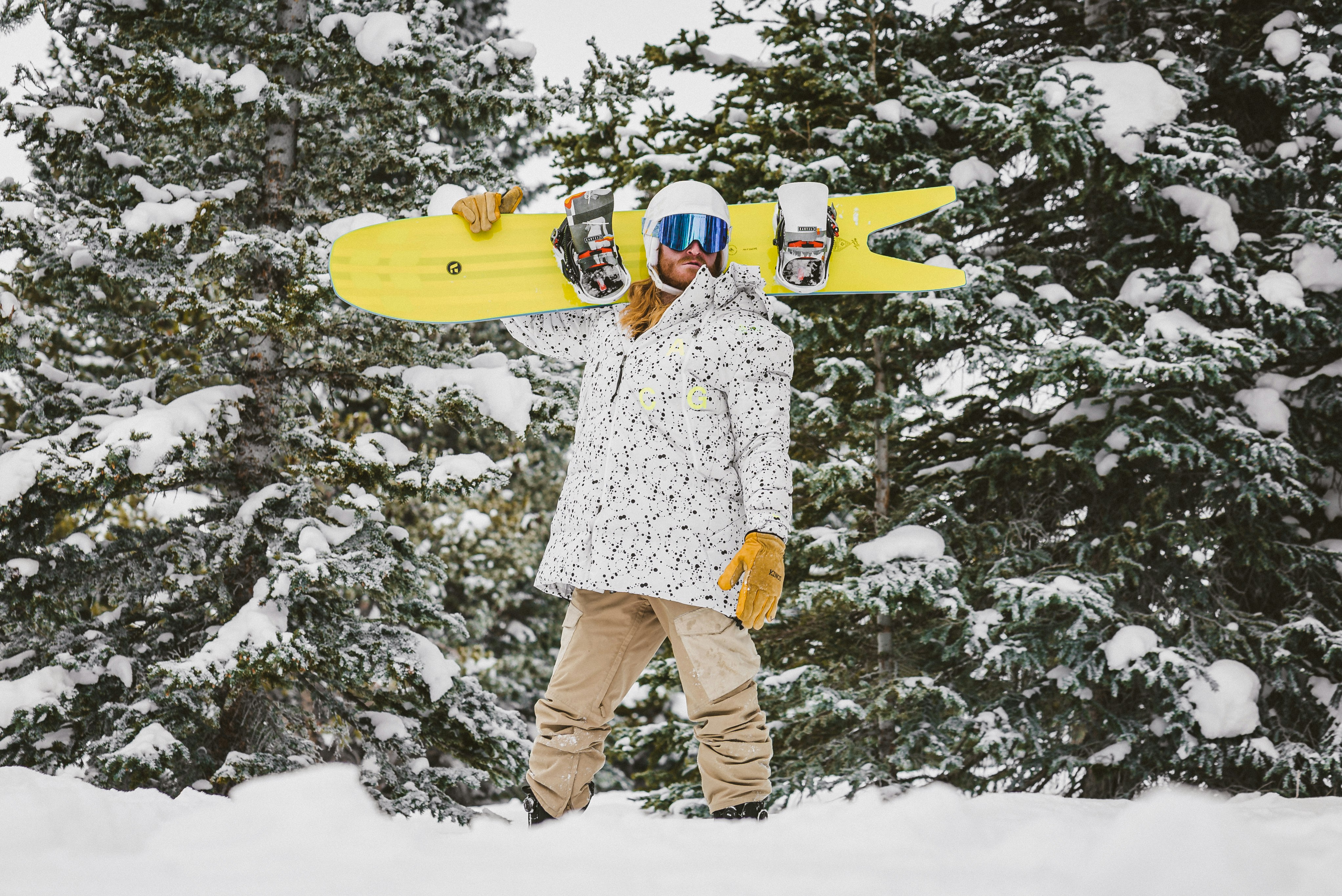 man in white and red floral dress shirt and brown pants holding yellow surfboard