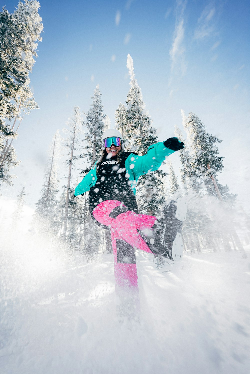 Person in blauer Jacke und rosa Hose, die tagsüber auf dem Snowboard fährt