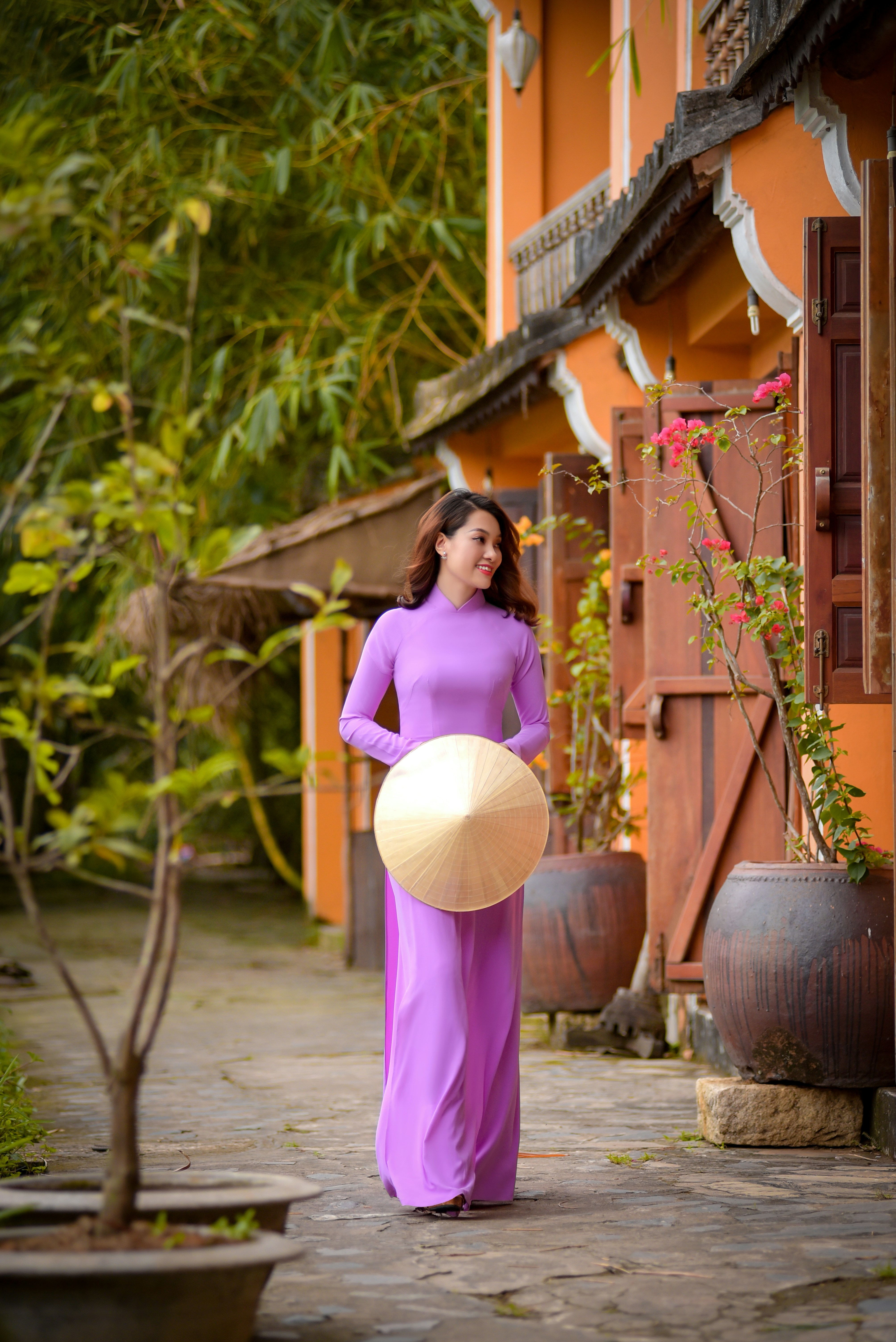 woman in purple dress holding brown wicker hat