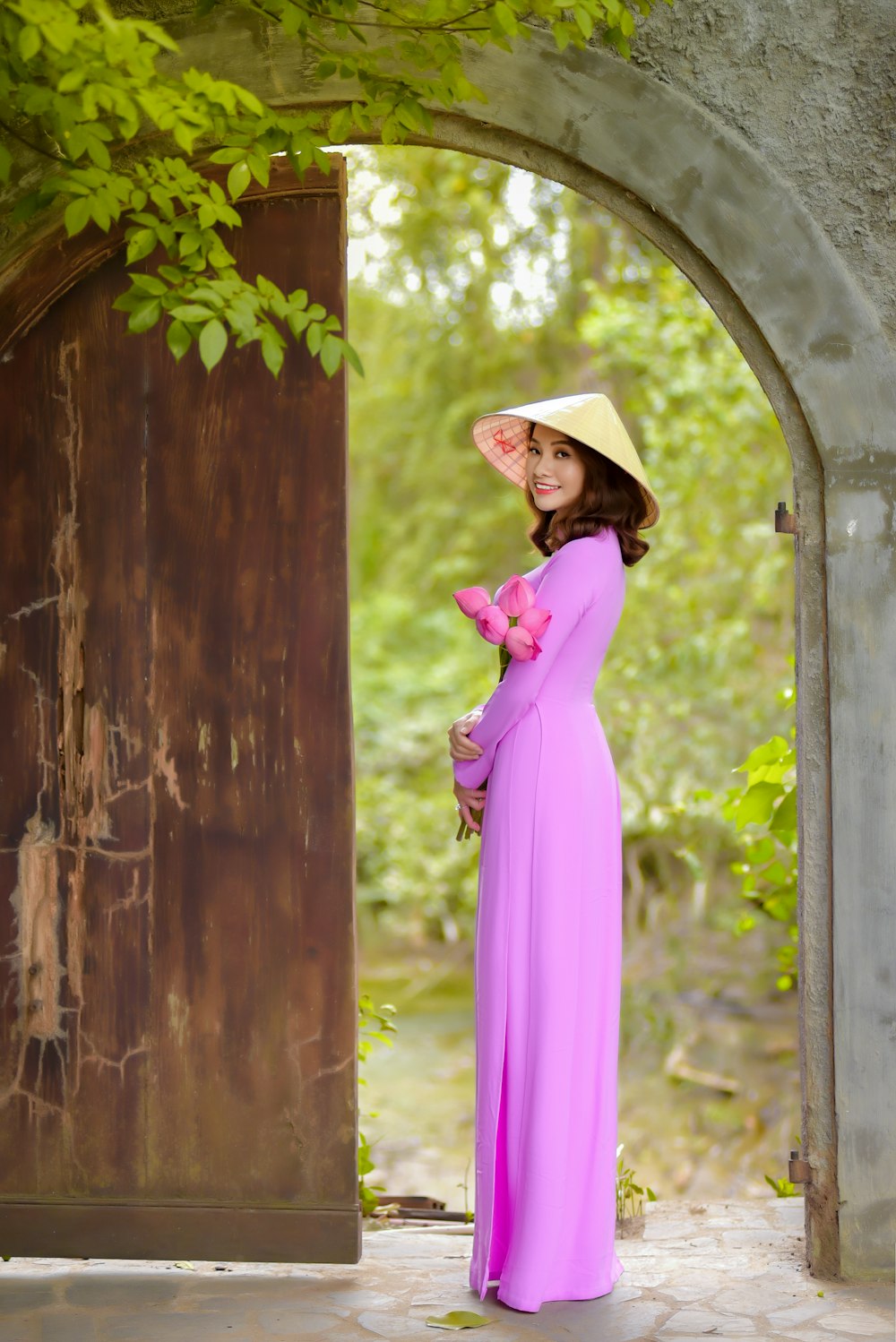 woman in purple long sleeve dress wearing brown hat standing beside brown wooden wall