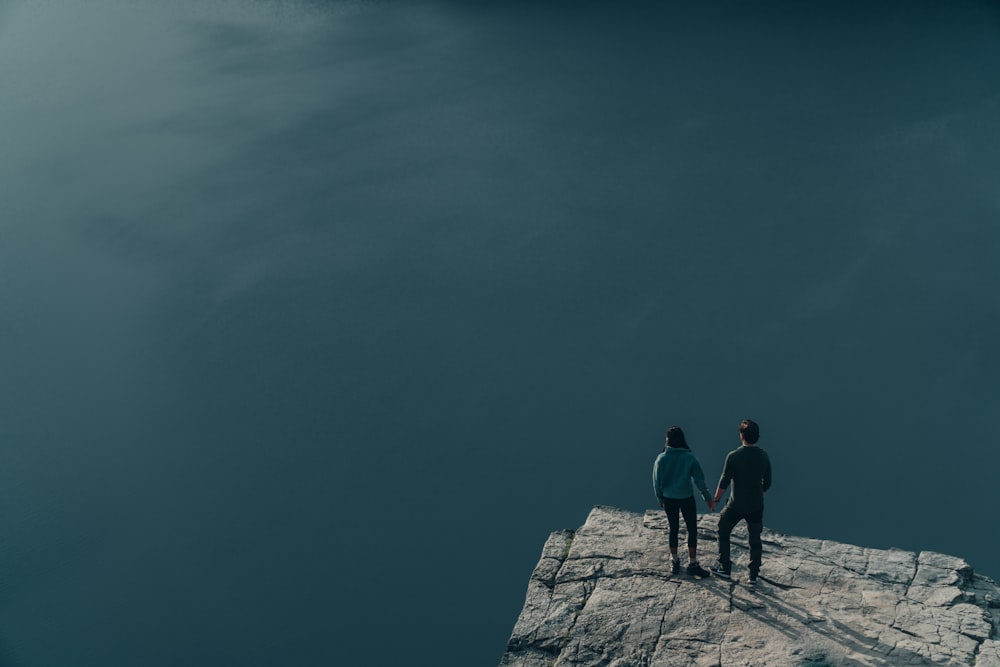 2 uomini in piedi sul molo di cemento grigio sotto il cielo blu durante il giorno