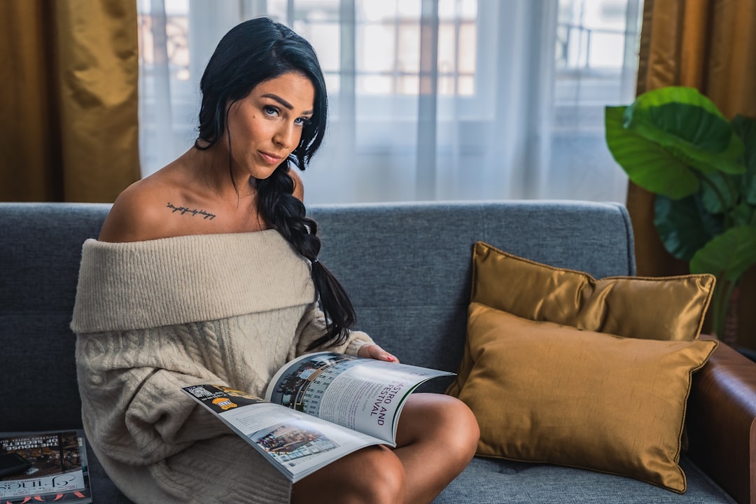 woman in white off shoulder dress reading book