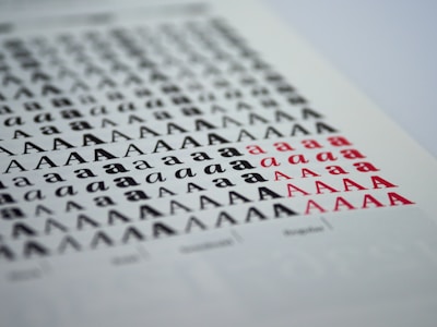 A sheet of paper displaying multiple rows of the letter 'A' in various styles, sizes, and colors. The letters transition from black to red, creating a pattern across the page.
