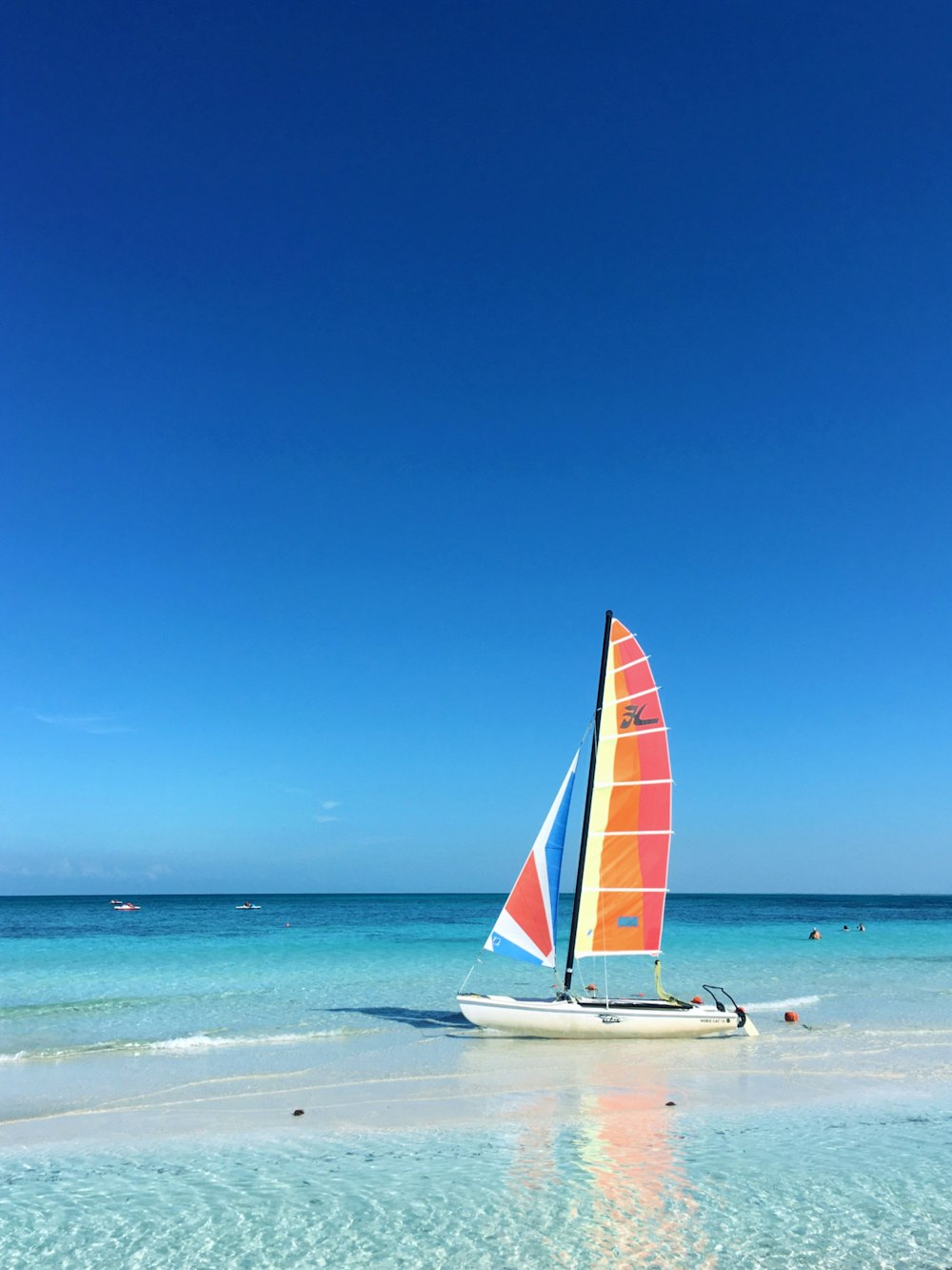 a sailboat on a beach with people in the water