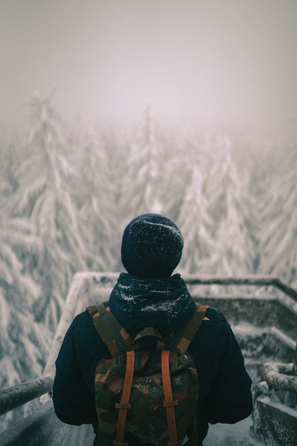 person in black jacket and black backpack standing on snow covered ground during daytime