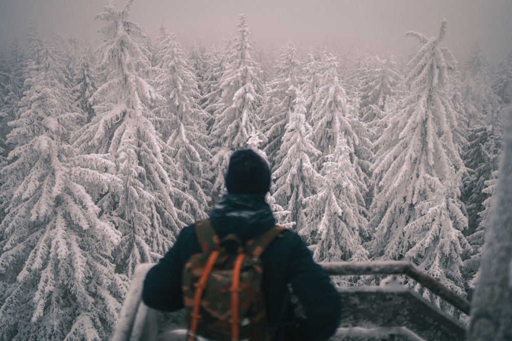 person in black jacket and black knit cap standing on snow covered ground