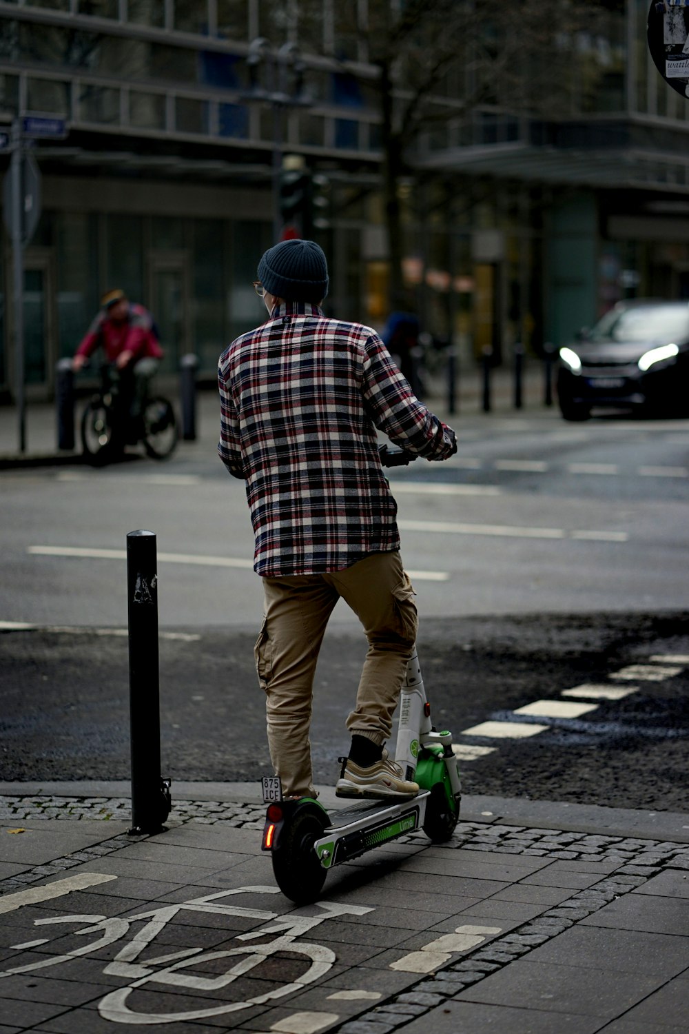 man in red and white plaid dress shirt and brown pants riding green and black skateboard