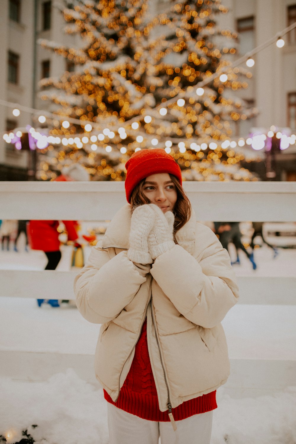 woman in red knit cap and white coat standing on snow covered ground