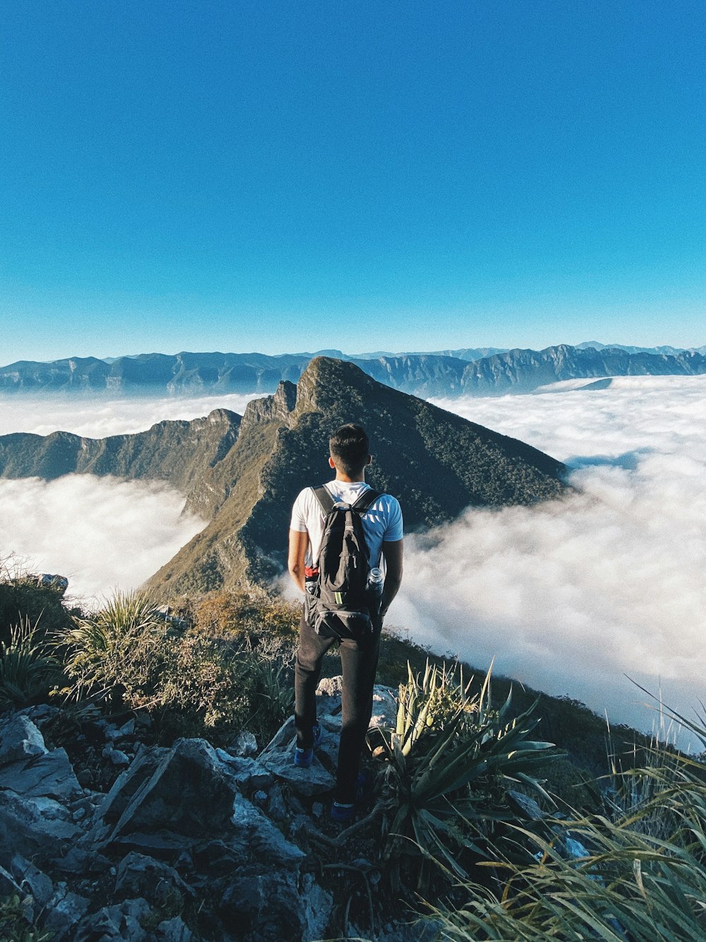 man in white shirt and black pants standing on rocky mountain during daytime