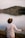 person in white long sleeve shirt wearing brown fedora hat standing near lake during daytime