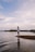 man in white shirt standing on brown rock near body of water during daytime
