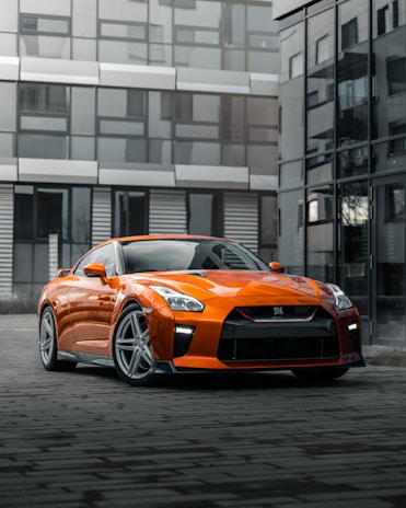 orange porsche 911 parked near building