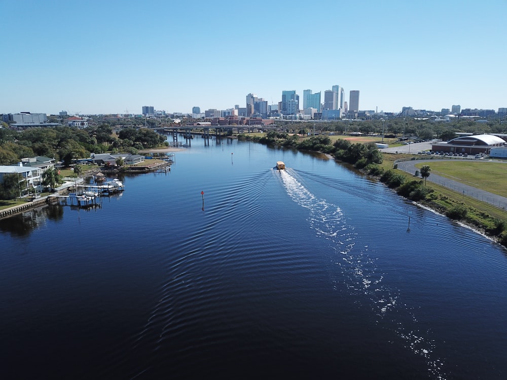 white boat on body of water near city buildings during daytime