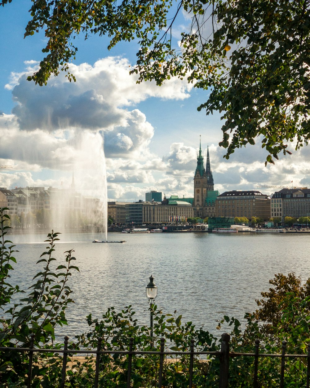 body of water near city buildings under blue and white sunny cloudy sky during daytime