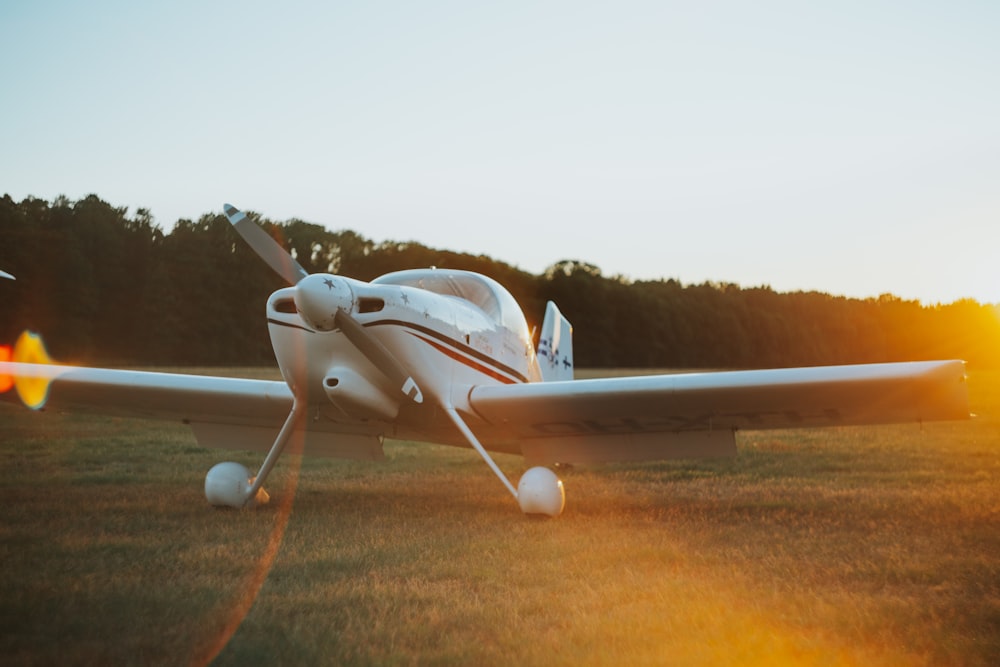 avião branco e vermelho no campo de grama marrom durante o dia