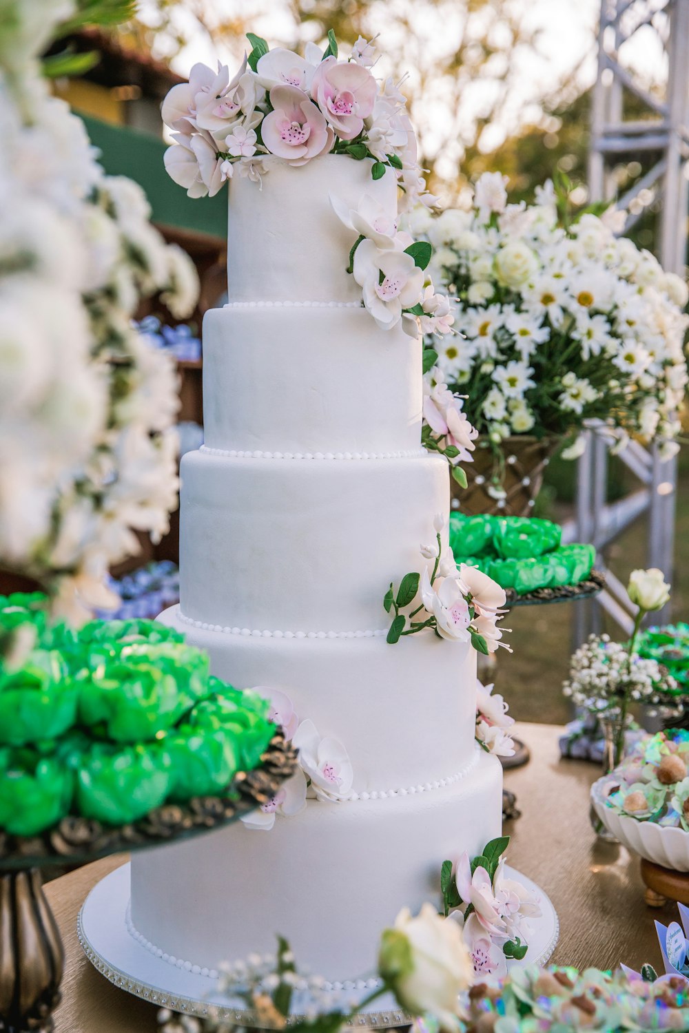 white 3 tier cake with green and pink flower accent