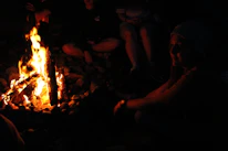 Close-up of smiling faces around a campfire during an outdoor trekking trip.
