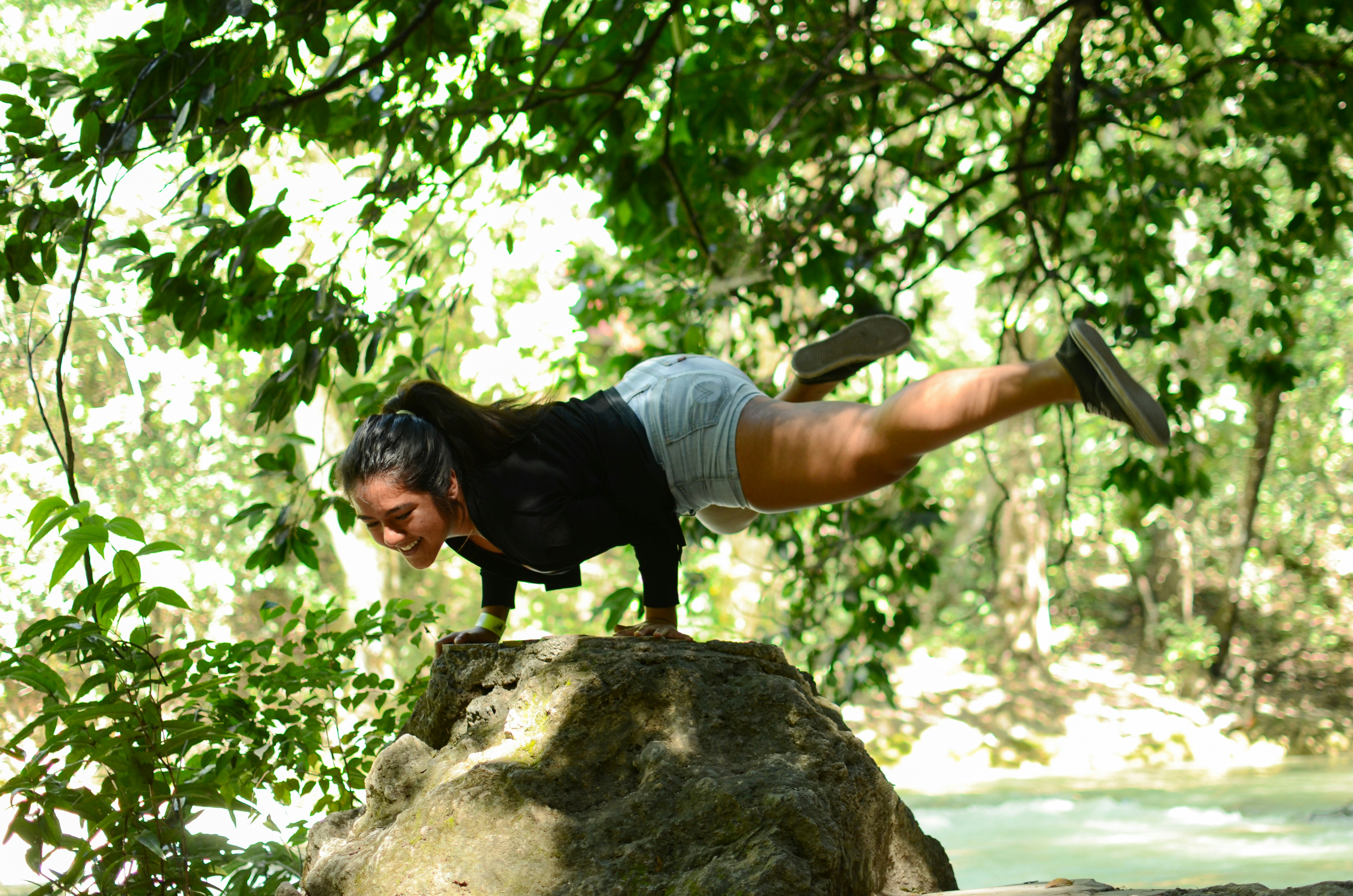 man in white t-shirt and black shorts sitting on brown rock during daytime