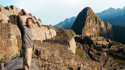 man in gray jacket standing on rocky hill during daytime