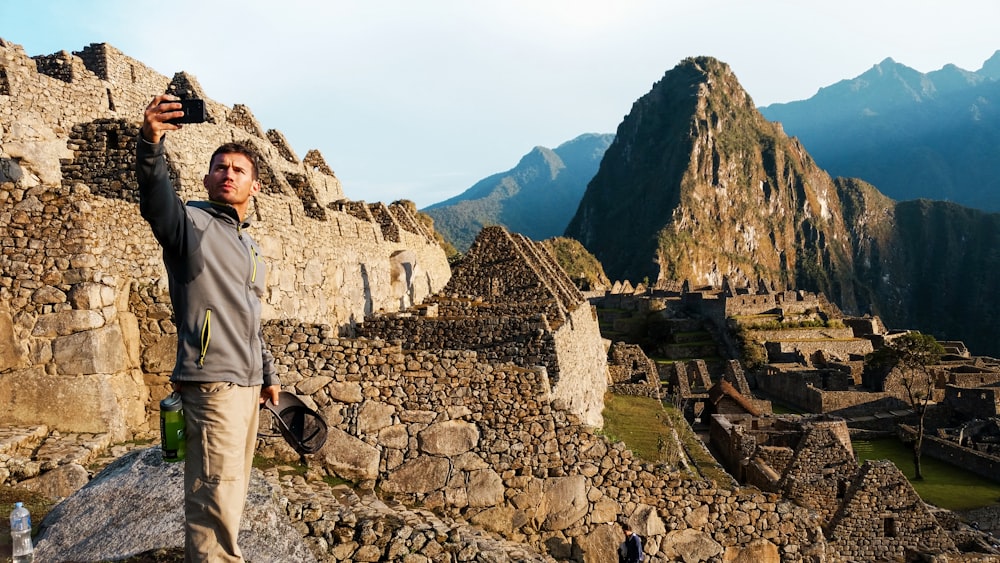 man in gray jacket standing on rocky hill during daytime