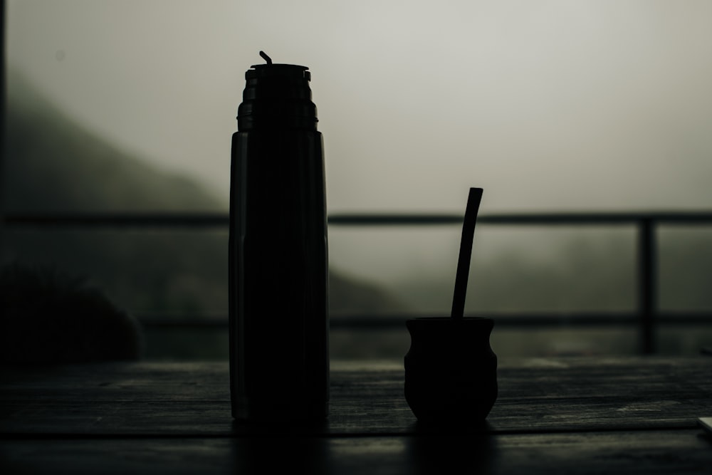black bottle with white straw on brown wooden table